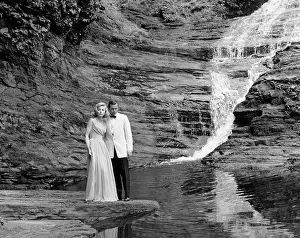 Hars Prints: 1970s COUPLE IN FORMAL DRESS STANDING ON ROCK AT SIDE OF CREEK WITH WATERFALL COMING DOWN BEHIND THEM