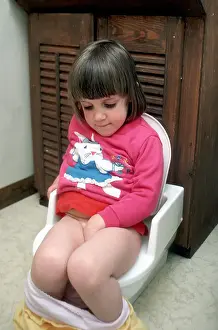 Sits Prints: 2 year old girl sits on small toilet as she becomes potty trained