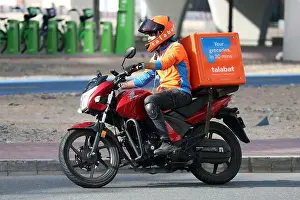 Landscape Format Prints: 22.03.2022, Dubai, , United Arab Emirates - Employee of food delivery service talabat riding a motorcycle in the city