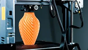 Creating Prints: 3D Printer printing a vase for home decoration with orange plastic Filament