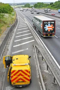 Occupations Prints: AA breakdown van parked on M25 motorway hard shoulder one mechanic working on broken down car out of sight under cover