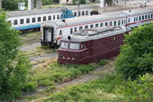 Carriage Prints: Abandoned soviet locomotive and passenger wagons on railroad tracks overgrown with grass