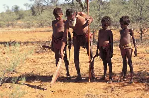 Learn Prints: Aboriginal elder points to track in desert sand with spear in teaching boys to hunt Central Australia