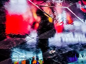 Abstract, artistic shot of silhouette of a person standing surrounded by neon light reflections seen in the reflection