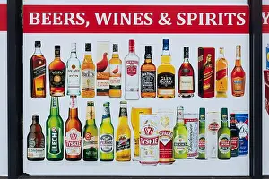Shop Window Prints: Advertising poster for beers, wines and spirits in the window of a convenience store, UK
