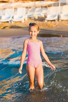 Sisters Prints: Adorable happy little girl playing in the sea on a beach