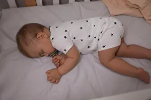 Asleep Prints: Adorable little baby with pacifier sleeping in crib, above view