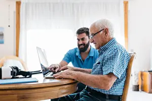 Explaining Prints: Adult grandson teaching his grandfather to use laptop