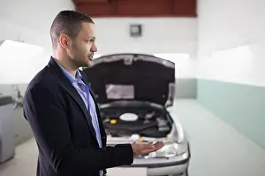 Explaining Prints: Adult man wearing blazer, blue shirt gesturing beside car with raised hood in garage