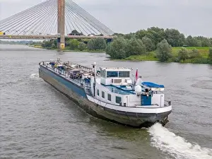Cargo Ship Prints: Aerial drone photo of a large cargo barge sailing on the river Waal in the Netherlans