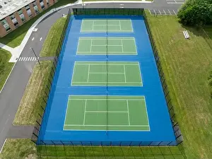 Aerial, drone, photo of new outdoor green tennis courts with white lines and blue out of bounds area