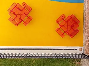 Equity Prints: Aerial, drone, photo, of a red vinyl coated picnic tables on a multi color playground surface