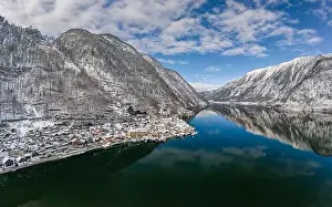 Northern Limestone Alps Prints: Aerial drone shot of Austrian snowy village by Hallstatt lake under blue sky in winter snowy time
