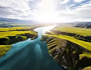 Almaty Prints: Aerial drone shot of beautiful scenery of blue mountain lake with green hills at sunset light glow in Tien Shan