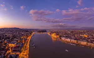 Beautiful Sky Prints: Aerial drone shot of Danube river with lighted quai with purple sky during Budapest sunset