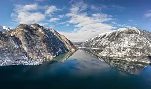 Northern Limestone Alps Prints: Aerial drone shot of ferry boat on Hallstatt lake with ripples in between snow mountains in Austria in winter before