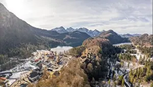 Aerial drone shot of Hohenschwangau by lake in Fussen with view of Alps snow mountain range in Germany winter