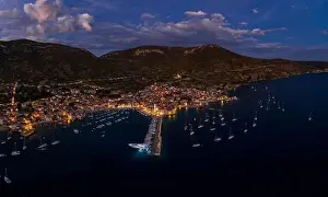 City Light Prints: Aerial drone shot of Komiza town port in night with city light on Vis Island in Croatia summer dusk