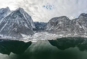 Aerial drone shot of Lahn village covered by snow by Hallstatt lake in Austria during winter