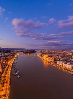 Beautiful Sky Prints: Aerial drone shot of lighted Hungarian Parliament by Danube river in purple Budapest sunset hour