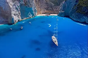 Noon Prints: Aerial drone shot of luxury yacht leaving Zakynthos shipwreck navagio beach in summer
