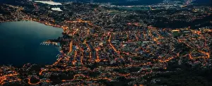 Aerial Cityscape Prints: Aerial drone shot panorama view of Lugano by lake after sunset with city lights on in Switzerland