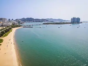 Aerial drone shot of Sanya bay beach with people and Phoenix island in background on Hainan island China