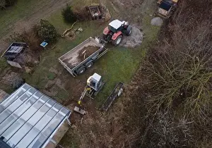 Mover Prints: aerial drone shot of small, yellow excavator stands in a large garden and digs a hole for a pool in austria