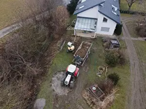 Mover Prints: aerial drone shot of small, yellow excavator stands in a large garden and digs a hole for a pool in austria