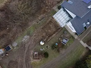 Mover Prints: aerial drone shot of small, yellow excavator stands in a large garden and digs a hole for a pool in austria