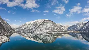 Northern Limestone Alps Prints: Aerial drone shot of snow covered hill with reflection by Hallstatt lake in Austria during winter time
