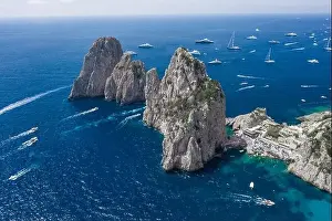 Aerial drone shot view of Faraglioni from east Capri Island in Tyrrhenian sea with Luxury yachts