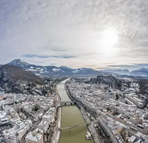 Salzach Prints: Aerial drone shot view of Salzach river across snowy Salzburg city covered with snow in winter morning