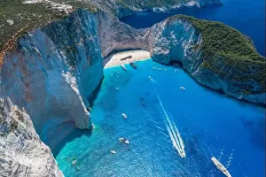 Noon Prints: Aerial drone shot of Zakynthos Navagio beach with tourists with cruise ship in blue Ionnian sea