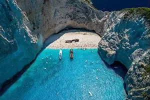 Noon Prints: Aerial drone shot of Zakynthos Navagio beach with tourists with cruise ship in blue Ionnian sea