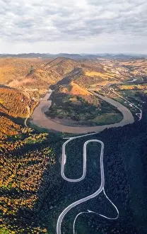 Aerial drone view over the autumn mountains with mountain road serpentine, river and forest. Landscape photography