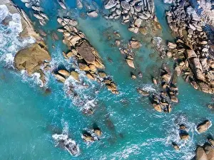 Aerial drone top view of beautiful waves crashing on the rocky island coast