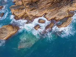 Aerial drone top view of beautiful waves crashing on the rocky island coast