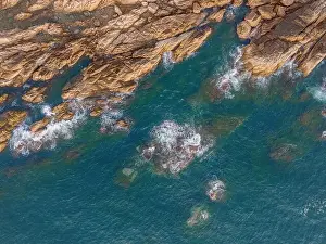 Aerial drone top view of beautiful waves crashing on the rocky island coast