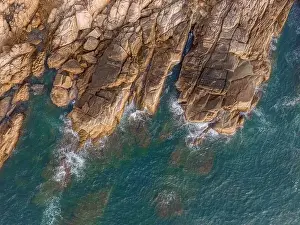 Aerial drone top view of beautiful waves crashing on the rocky island coast