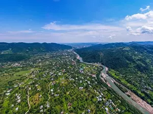 Valley Hill Prints: Aerial drone view of green mountain, pine forest, river and village. Carpathian, Ukraine