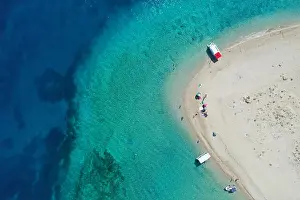 Aerial drone view of iconic small uninhabited island of Marathonisi featuring clear water, sandy shore and natural hatchery of Caretta-Caretta sea tur