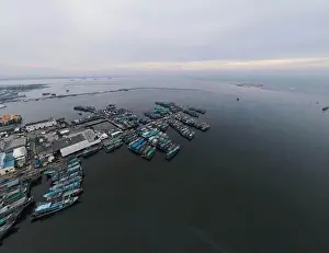 Wooden Boat Prints: Aerial drone view of Muara Angke Beach with wooden boats leaning beside the pier