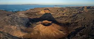 Lanzarote Prints: The aerial image captures a vast volcanic landscape bathed in the warm light of sunset