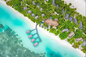 Aerial landscape from drone view blue water and wooden bridge and water villas with paradise island shore, sea coast palm tree. Stunning aerial travel