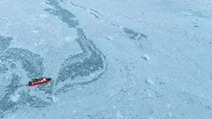 Blue Ice Prints: Aerial of a little ship floating between the ice below the Eqi glacier