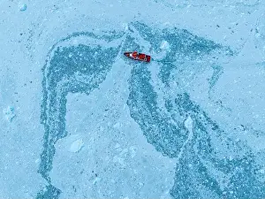 Open Water Prints: Aerial of a little ship floating between the ice below the Eqi glacier