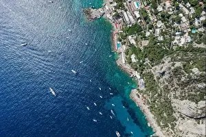 Aerial overhead drone shot of southern Capri Island coastline with yachts in summer noon