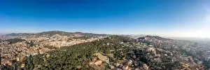 Aerial panorama drone shot of of hill near Barcelona city in morning hour with view of agbar tower in distatnt in Spain