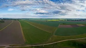Panorama Hill Prints: Aerial panorama of vast farmland with alternating crop fields under a partly cloudy sky